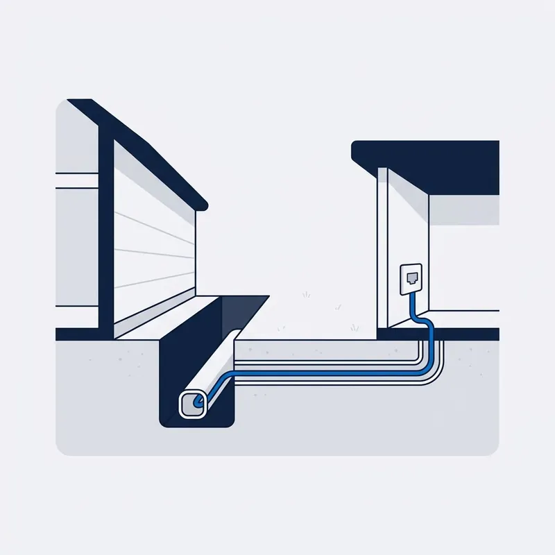 Illustration: a section through the yard between the house and the flat, conduit in the trench carrying the cable to a socket on the flat's wall